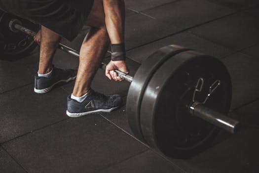 Machines Guidées ou Fonctionnel : la force qui compte vraiment ? A man lifting a heavy barbell during a gym workout, showcasing strength and fitness.
